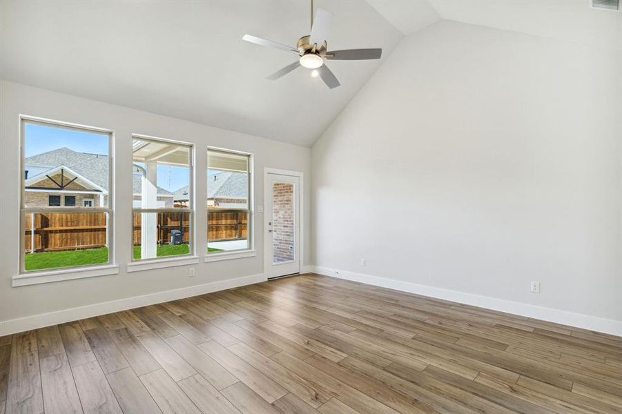 Spare room with high vaulted ceiling, ceiling fan, and light hardwood / wood-style flooring