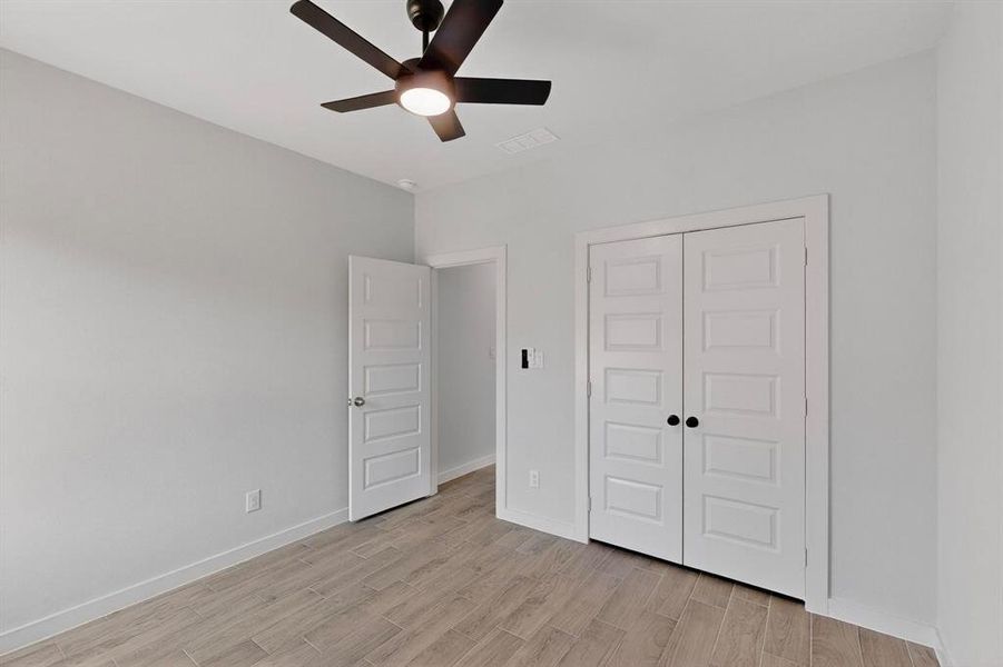 Unfurnished bedroom featuring light wood-type flooring, ceiling fan, and a closet Unfurnished bedroom featuring light wood-type flooring, ceiling fan, and a closet