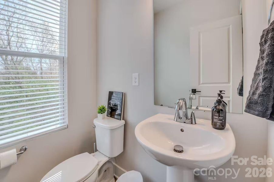 A convenient main-level powder room features a pedestal sink, abundant natural light, and modern finishes, making it ideal for guests. A convenient main-level powder room features a pedestal sink, abundant natural light, and modern finishes, making it ideal for guests.