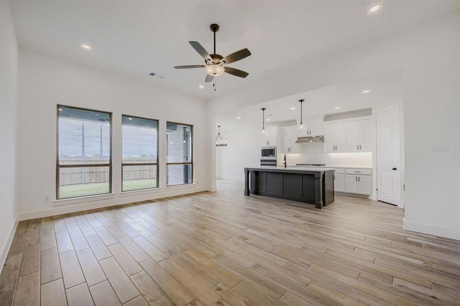 Open-concept main living area with wood-finish flooring, recessed lighting, and a ceiling fan