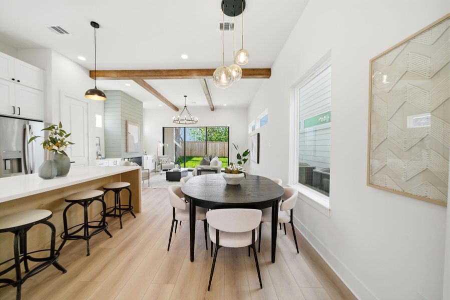 This photo showcases a modern open-concept living area with a sleek kitchen, dining space, and living room. The kitchen includes a spacious island with barstools, while the dining area has a round table with stylish chairs.