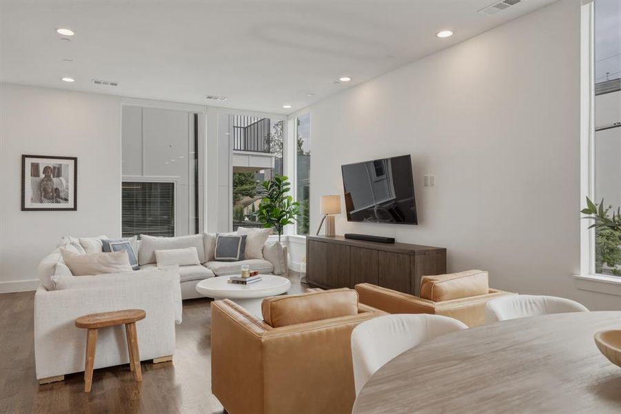 Living area featuring dark hardwood floors, recessed lighting, and large windows providing ample natural light