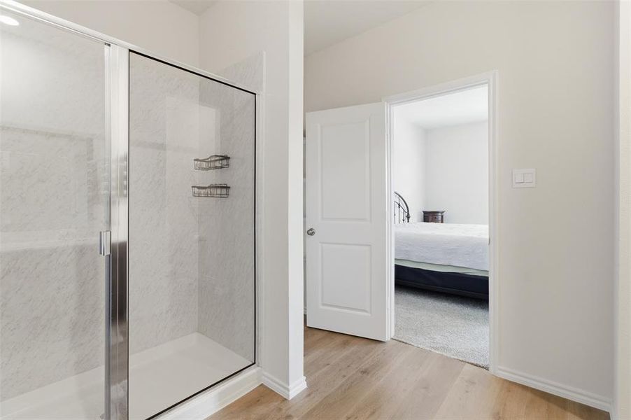 Full bath featuring ensuite bath, a marble finish shower, and light wood finished floors Full bath featuring ensuite bath, a marble finish shower, and light wood finished floors