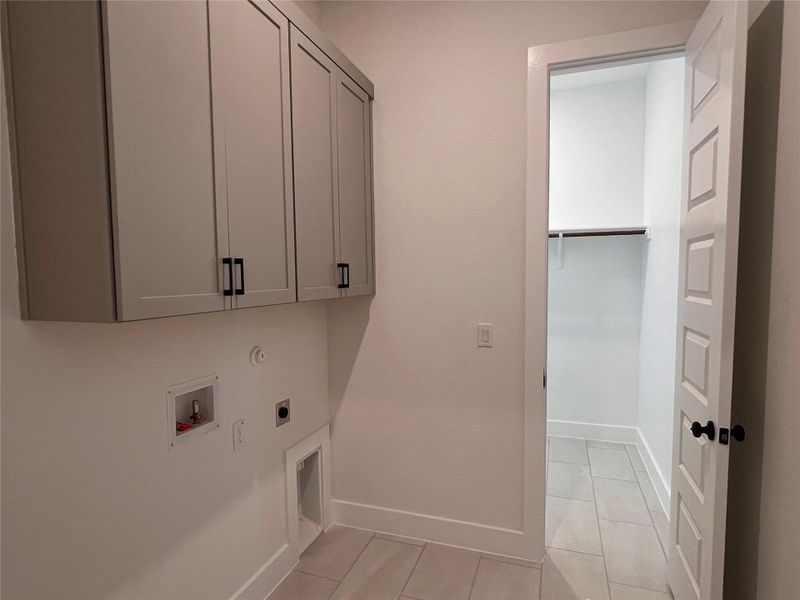 Laundry room featuring electric dryer hookup, cabinet space, washer hookup, light tile patterned floors, and gas dryer hookup