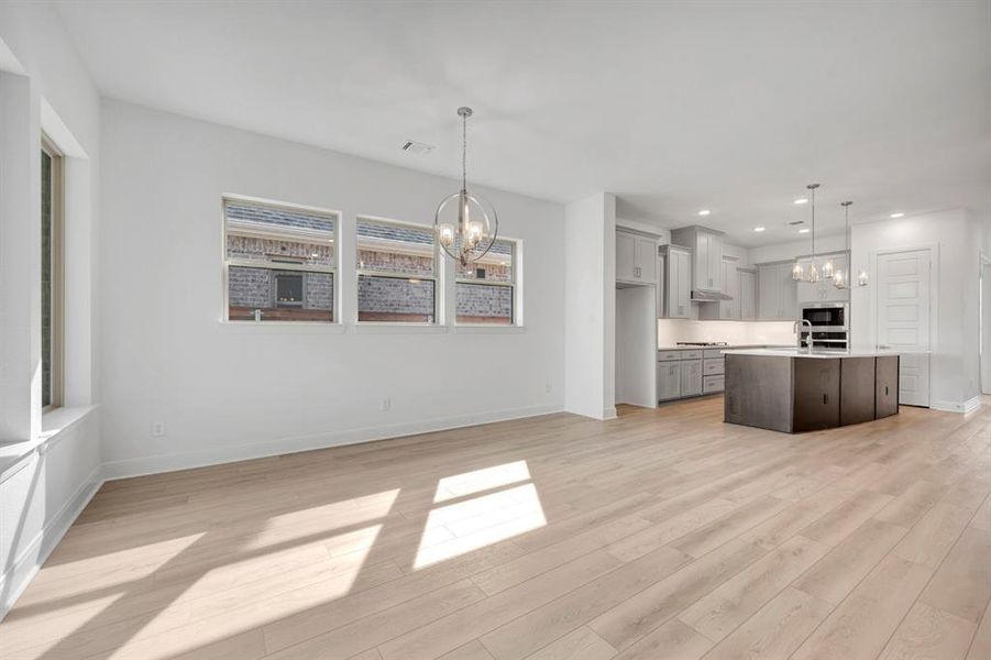 Kitchen featuring a chandelier, light wood finished floors, and a kitchen island with sink Kitchen featuring a chandelier, light wood finished floors, and a kitchen island with sink