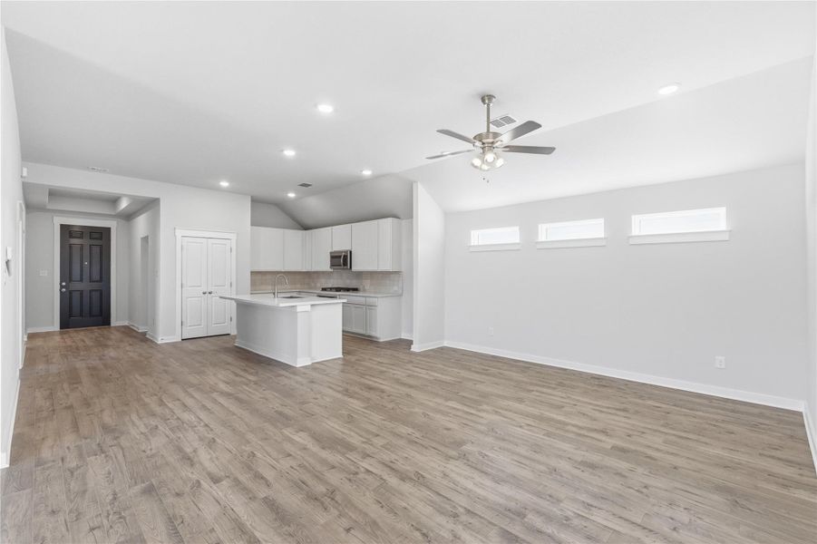 Kitchen featuring open floor plan, light countertops, white cabinetry, an island with sink, and tasteful backsplash