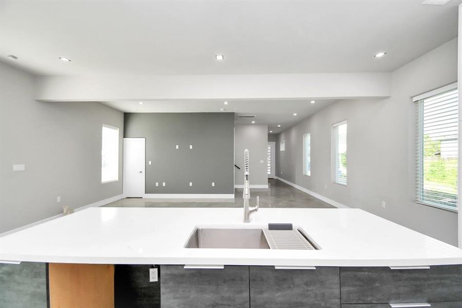 Modern kitchen featuring white cabinetry, sleek countertops, a central island, and high-end stainless-steel fixtures, complemented by a subtle grey painted backsplash.