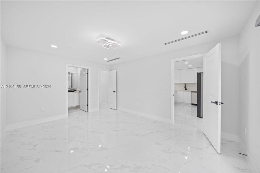 White tile flooring, recessed lighting, modern ceiling light fixture, white walls, white interior doors White tile flooring, recessed lighting, modern ceiling light fixture, white walls, white interior doors