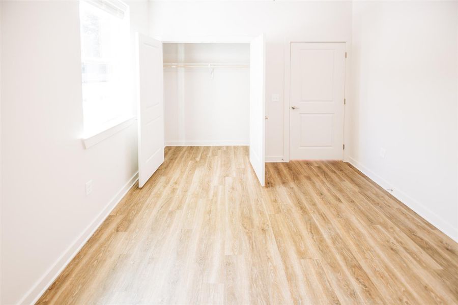 Unfurnished bedroom featuring light wood-style flooring, a closet, and baseboards