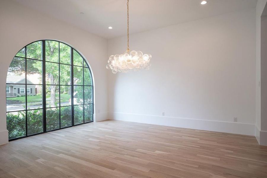 Empty room with a notable chandelier and light wood-type flooring