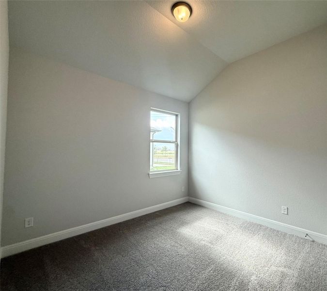 Empty room with vaulted ceiling and dark carpet Empty room with vaulted ceiling and dark carpet