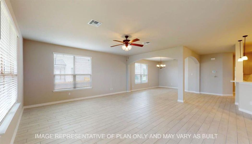 Unfurnished living room with ceiling fan, a chandelier, arched walkways, and light wood finished floors Unfurnished living room with ceiling fan, a chandelier, arched walkways, and light wood finished floors