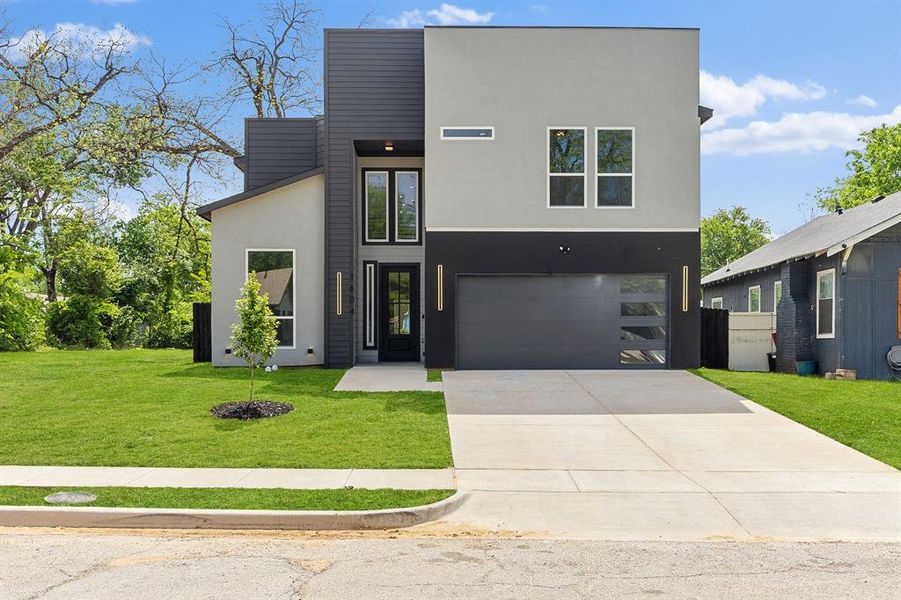 The property presents a contemporary facade with a contrasting grey and black exterior, featuring large windows and a modern garage door The property presents a contemporary facade with a contrasting grey and black exterior, featuring large windows and a modern garage door
