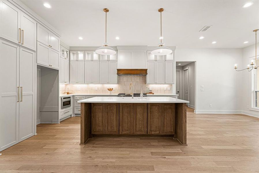 Kitchen featuring glass insert cabinets, white cabinets, decorative light fixtures, tasteful backsplash, and recessed lighting