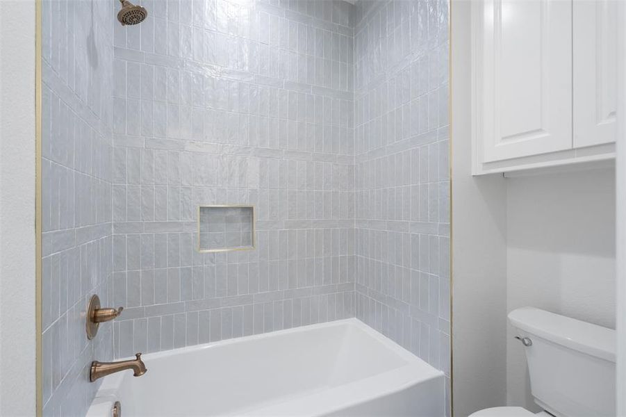 Bathroom with tiled shower / bath combo and toilet