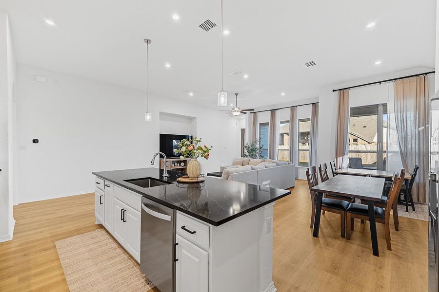 Kitchen with white cabinetry, open floor plan, decorative light fixtures, a ceiling fan, and light wood-style flooring