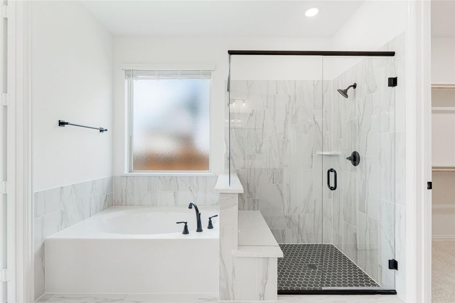 Master bathroom with soaking tub, glass-enclosed shower, marble tile walls, and black fixtures