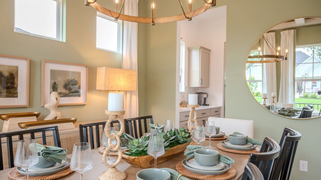 Dining area with coffered ceiling, access to kitchen, and bright natural lighting from windows Dining area with coffered ceiling, access to kitchen, and bright natural lighting from windows