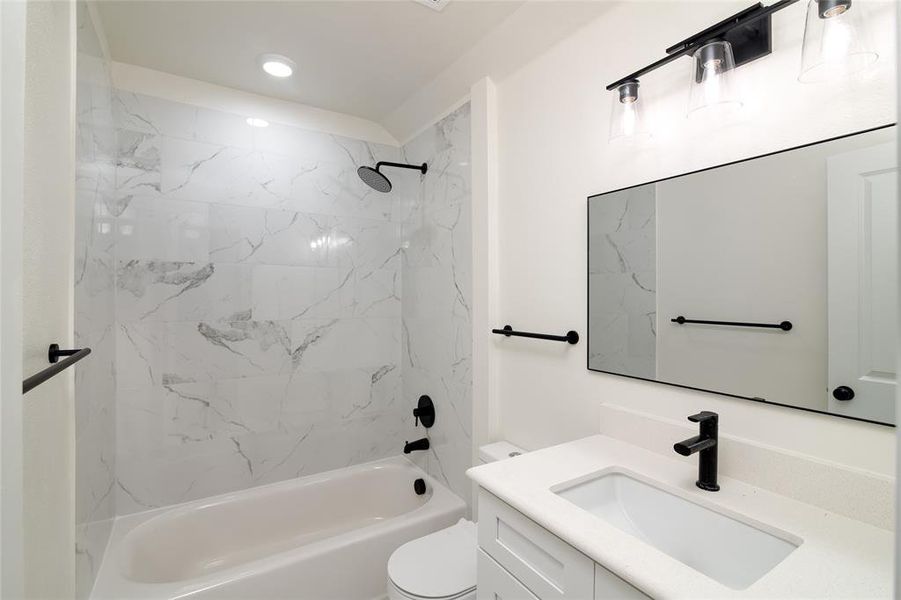 Full bathroom featuring tiled shower / bath combo, vanity, and toilet