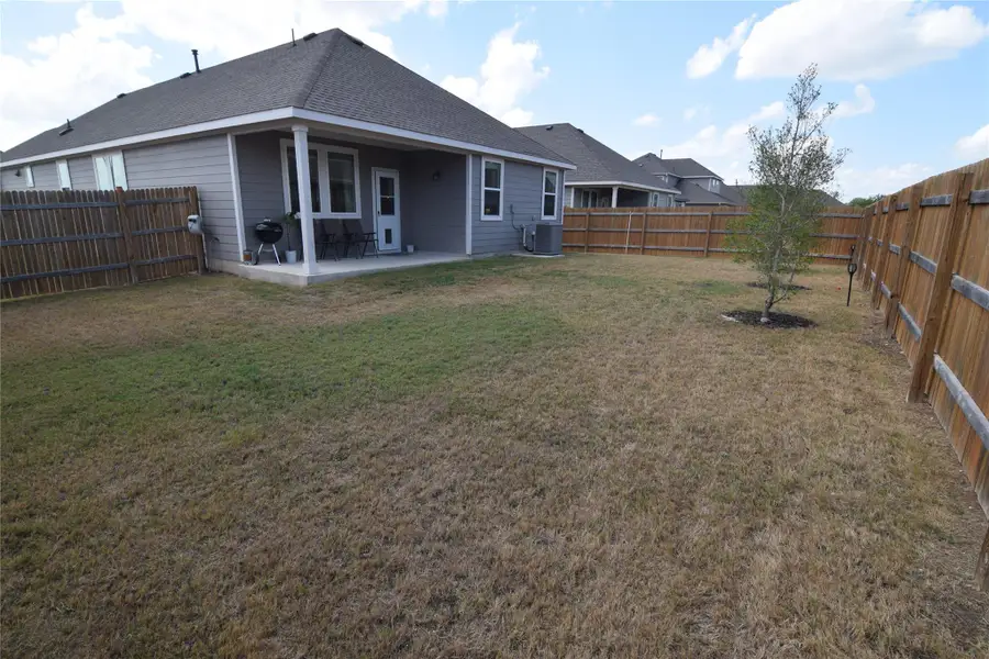 A spacious grassy yard is fully enclosed by tall wood privacy fencing.