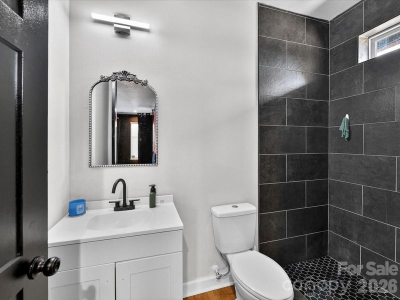 Modern ensuite bathroom featuring a sleek vanity, matte black fixtures, and a walk-in shower with bold dark tile accents.