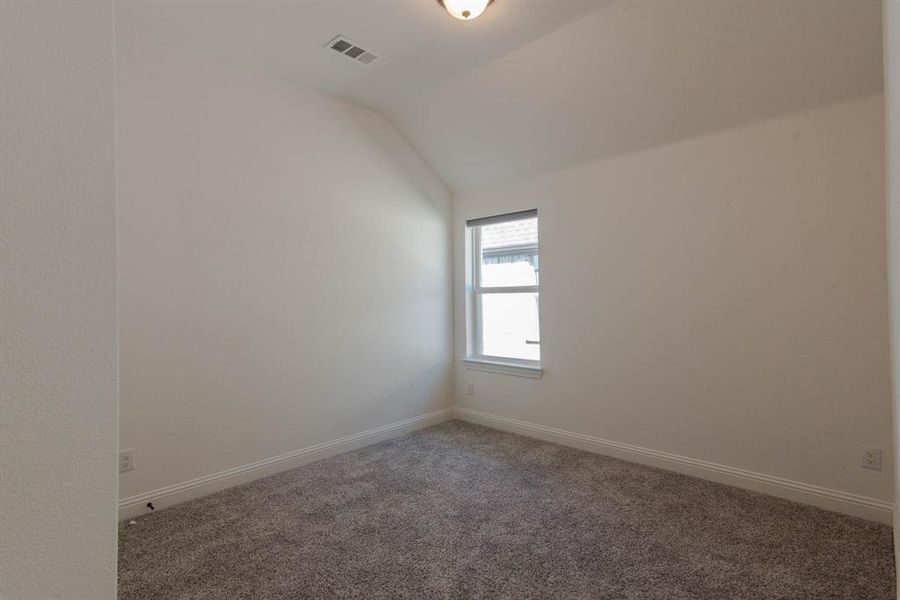 Carpeted empty room with lofted ceiling