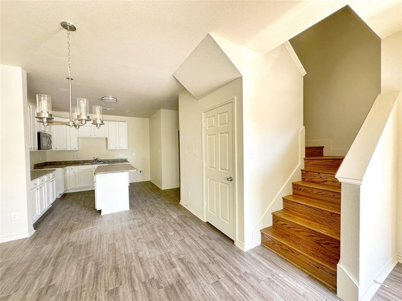 Kitchen featuring white cabinets, light wood-type flooring, a chandelier, a kitchen island, and stainless steel microwave