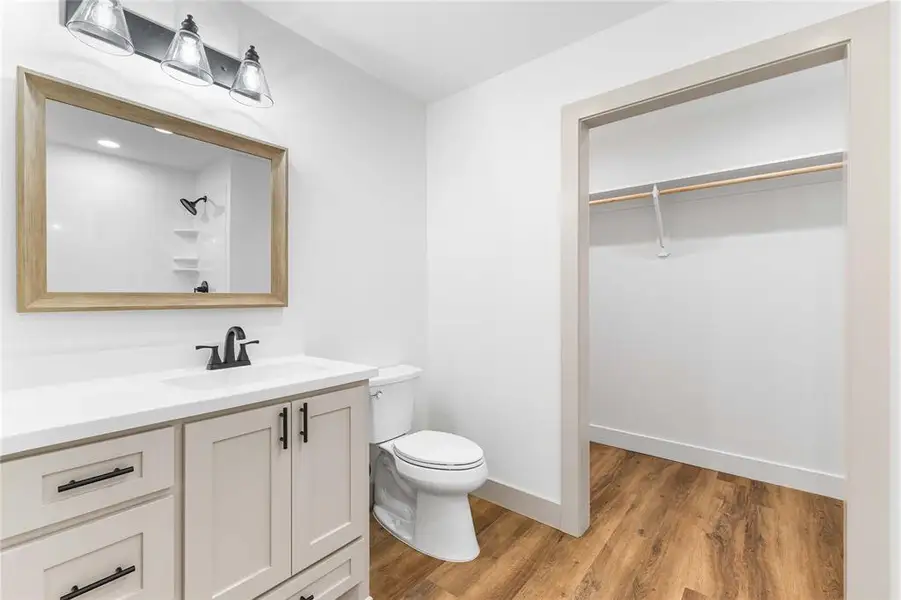 Full bathroom featuring light wood-style flooring, vanity, a spacious closet, and a shower Full bathroom featuring light wood-style flooring, vanity, a spacious closet, and a shower