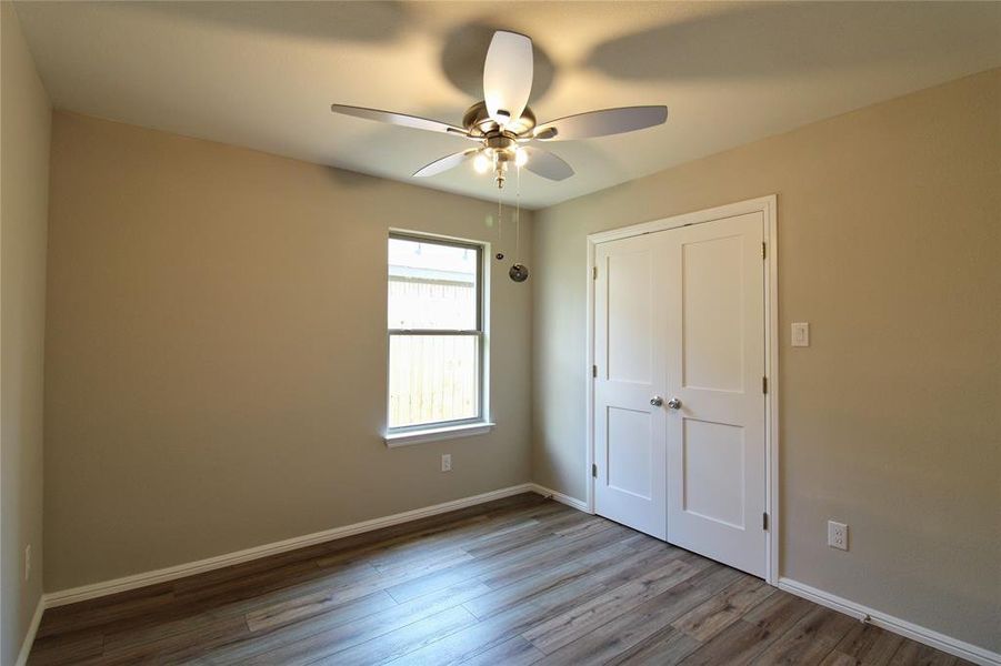 Unfurnished bedroom with wood finished floors, ceiling fan, and a closet