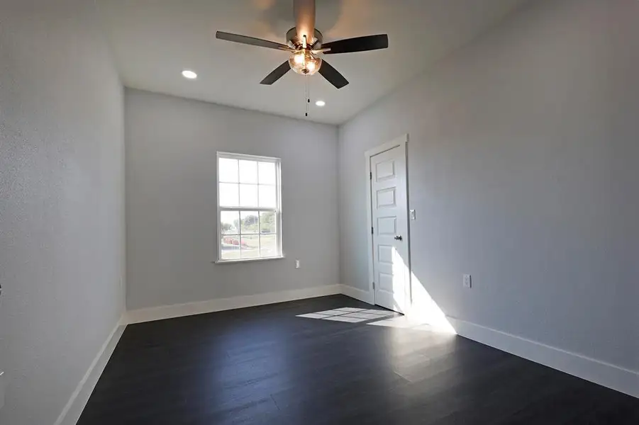 Empty room with dark wood-type flooring, ceiling fan, and recessed lighting Empty room with dark wood-type flooring, ceiling fan, and recessed lighting