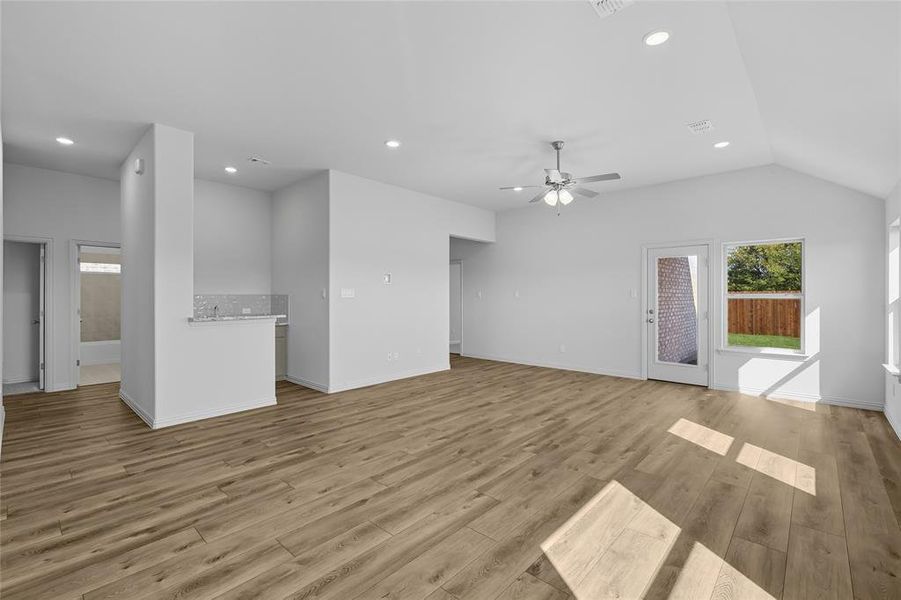 Unfurnished living room featuring recessed lighting, light wood-style floors, lofted ceiling, and a ceiling fan Unfurnished living room featuring recessed lighting, light wood-style floors, lofted ceiling, and a ceiling fan