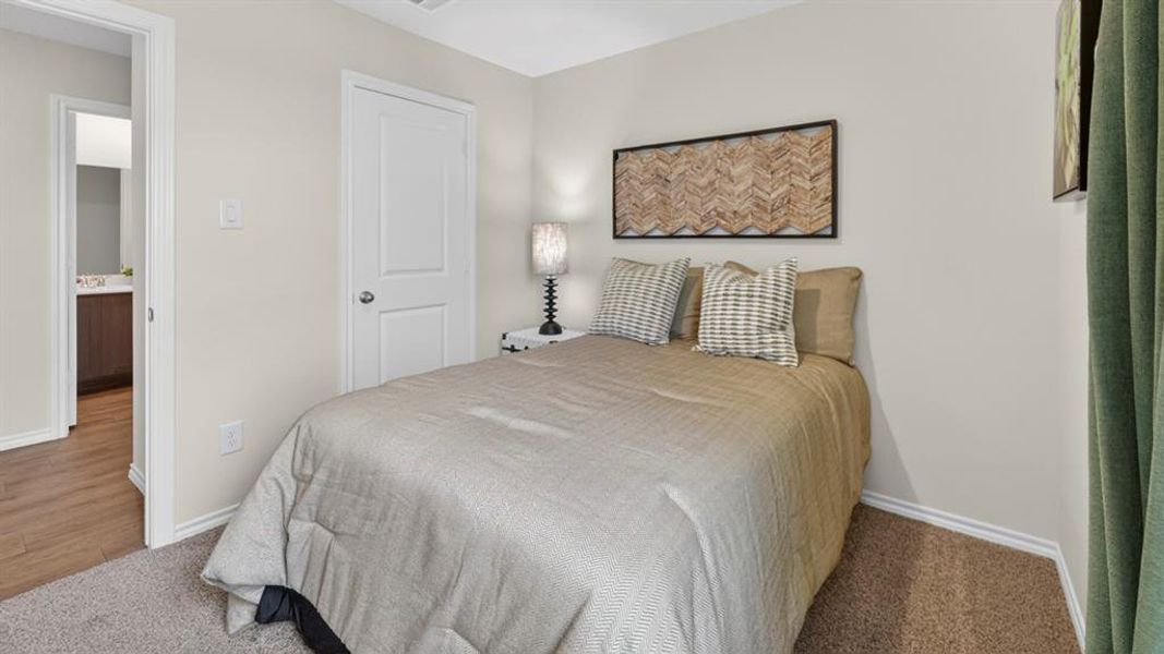 Carpeted bedroom featuring neutral wall tones, white trim, and a paneled door Carpeted bedroom featuring neutral wall tones, white trim, and a paneled door