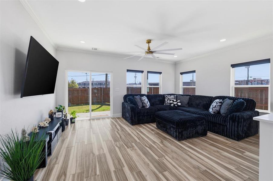 Living area featuring a ceiling fan, light wood-style floors, ornamental molding, and recessed lighting
