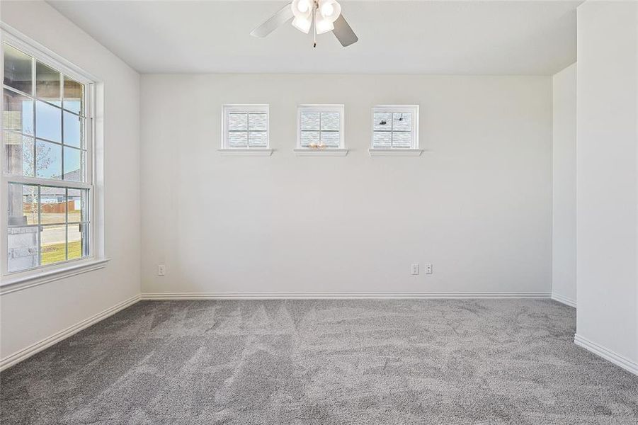 Carpeted spare room featuring ceiling fan and plenty of natural light