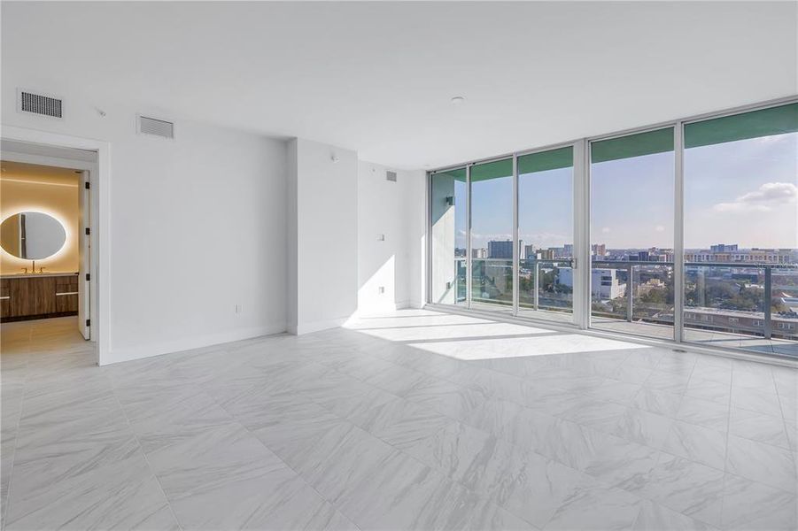 Living room showing off a peek-a-boo view to the primary bathroom and a stunning view over the city