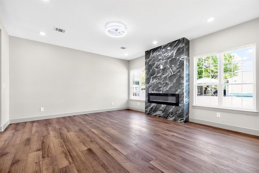 Unfurnished living room with a high end fireplace, dark wood-style floors, and recessed lighting Unfurnished living room with a high end fireplace, dark wood-style floors, and recessed lighting