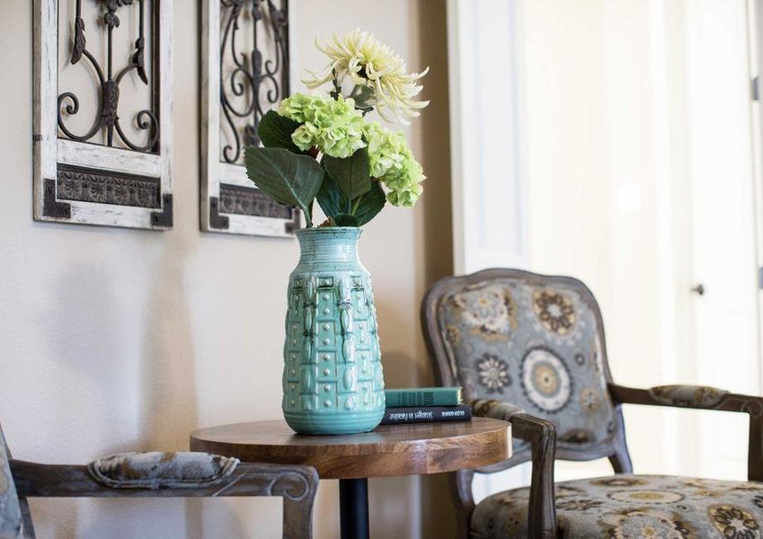 Sitting area with arm chairs and floral arrangement.