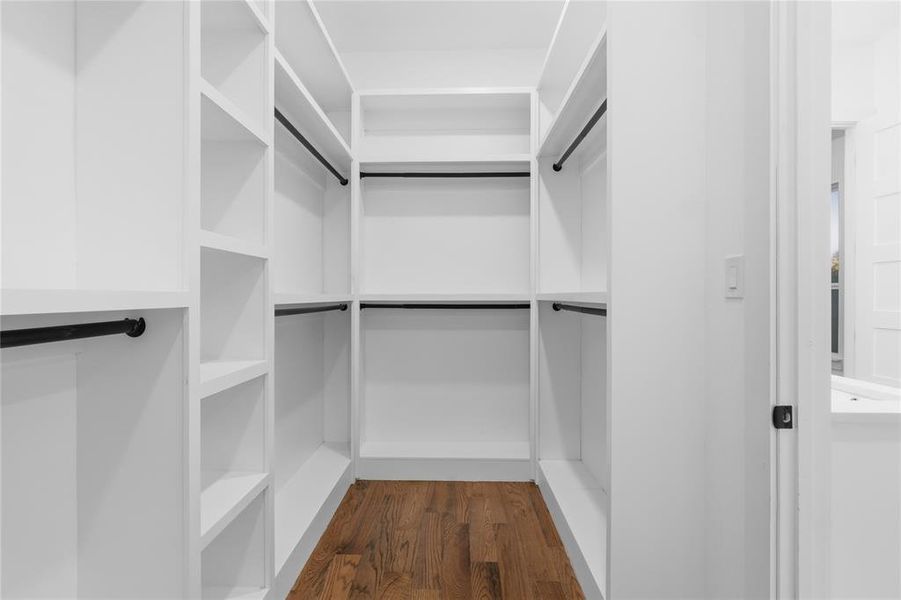 Walk in closet with dark wood-style flooring