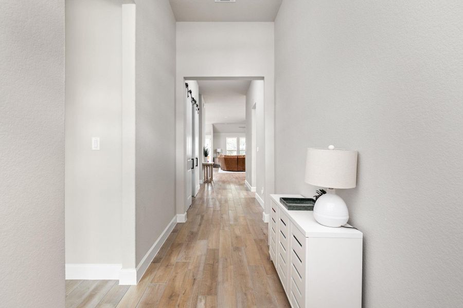 Hall with light wood-style floors, a textured wall, and a barn door