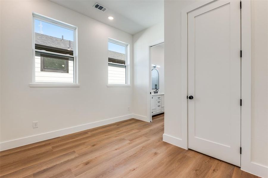 Unfurnished bedroom featuring connected bathroom, light wood-type flooring, and recessed lighting