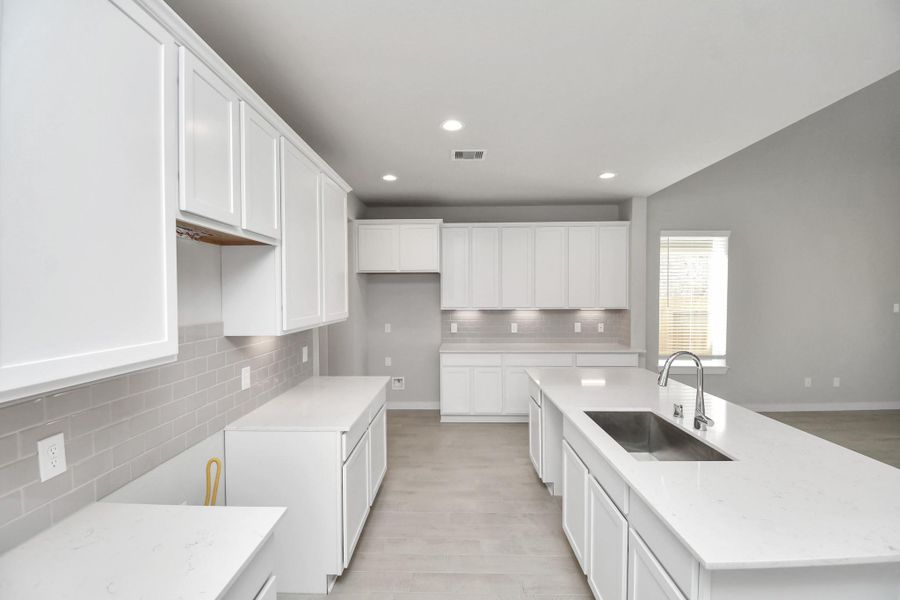 The kitchen is a culinary haven, featuring granite countertops, a tile backsplash, stainless steel appliances, 42” upper cabinets, and undercabinet lighting. Sample photo of completed home with similar floor plan. Actual colors and selections may vary.