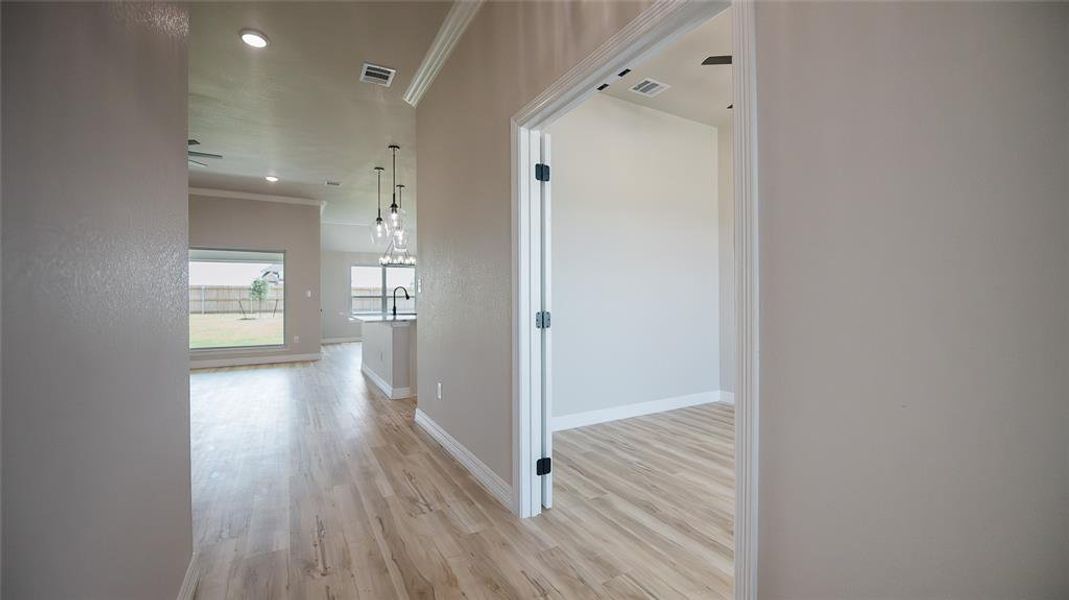 Corridor with ornamental molding, light wood-type flooring, and recessed lighting Corridor with ornamental molding, light wood-type flooring, and recessed lighting