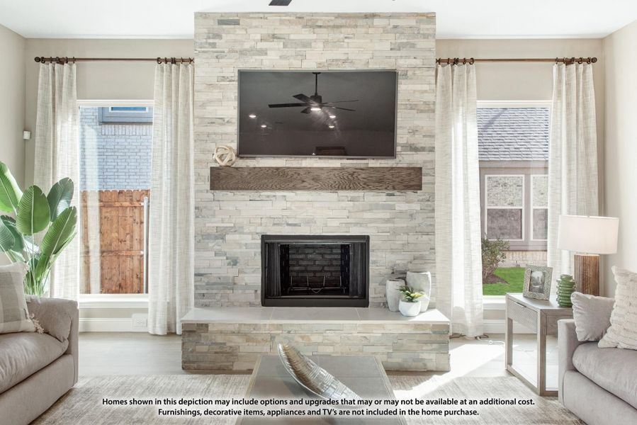 Living room with floor-to-ceiling stacked stone fireplace, wood mantel, wall-mounted TV, and large windows with white drapes. Living room with floor-to-ceiling stacked stone fireplace, wood mantel, wall-mounted TV, and large windows with white drapes.