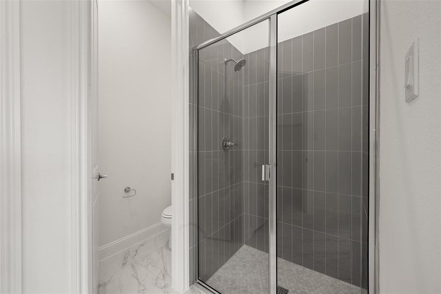 Bathroom featuring marble look tiles and a shower stall Bathroom featuring marble look tiles and a shower stall