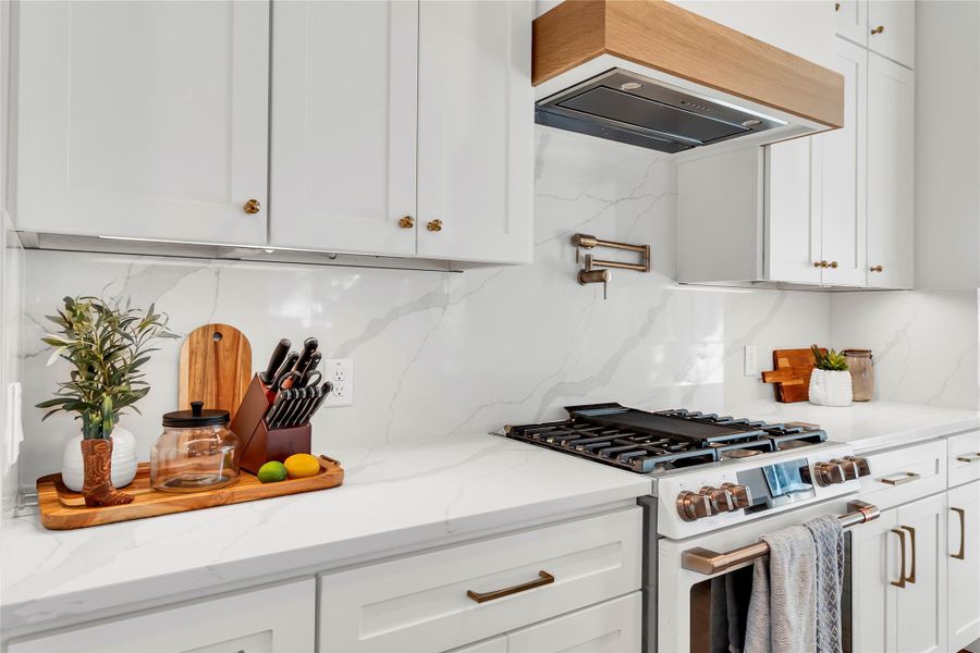 Kitchen featuring white gas range, light stone countertops, white cabinets, and decorative backsplash Kitchen featuring white gas range, light stone countertops, white cabinets, and decorative backsplash