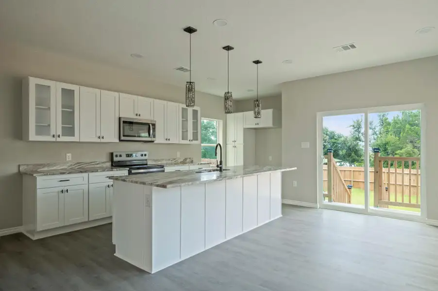 Kitchen with glass insert cabinets, white cabinetry, decorative light fixtures, an island with sink, and recessed lighting