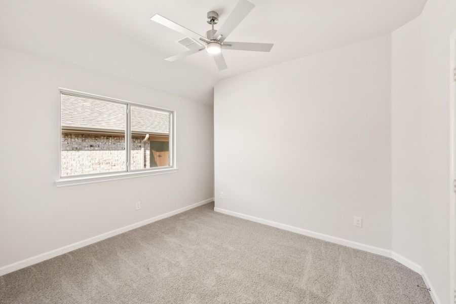 Empty bedroom with gray carpet, ceiling fan, and single window with white walls Empty bedroom with gray carpet, ceiling fan, and single window with white walls