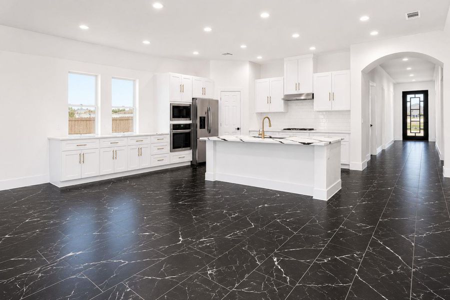 An open-concept kitchen features a large island and ample cabinet storage.
