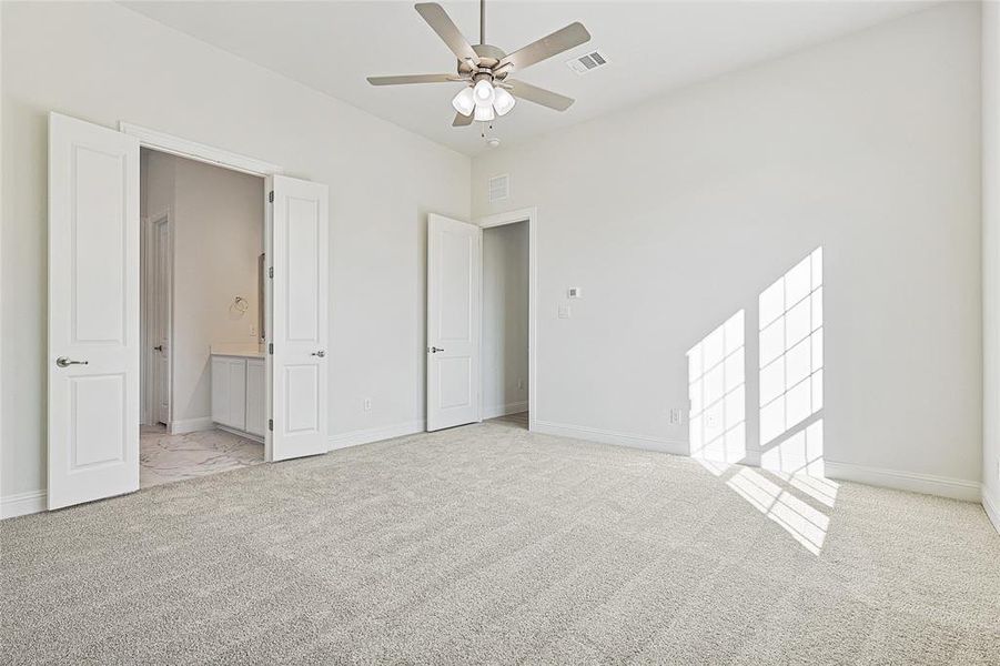 Unfurnished bedroom featuring connected bathroom, ceiling fan, and light colored carpet