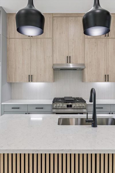 Close-up kitchen detail featuring pendant lighting, island sink, and wood accents Close-up kitchen detail featuring pendant lighting, island sink, and wood accents